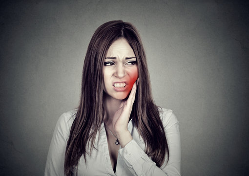 woman with sensitive toothache suffering from pain touching outside mouth .
