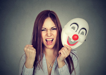 Angry screaming woman taking off clown mask expressing happiness