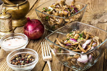 Marinated mushrooms and onions in a glass salad bowl