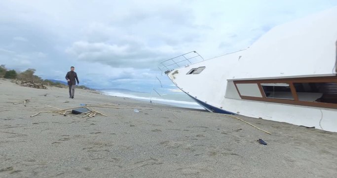 Ragazzo che passeggia sulla spiaggia scopre una valigetta vicino a una barca arenata