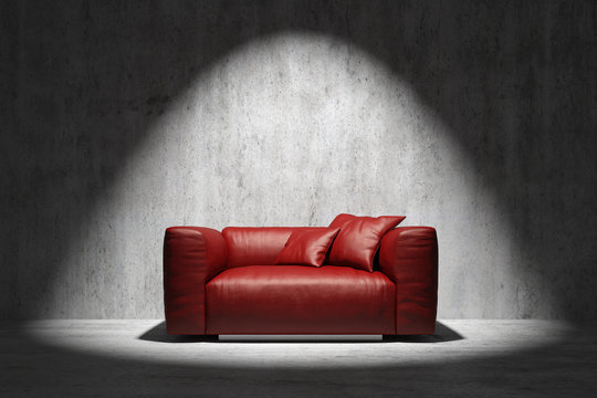 red sofa in front of a concrete wall with spotight