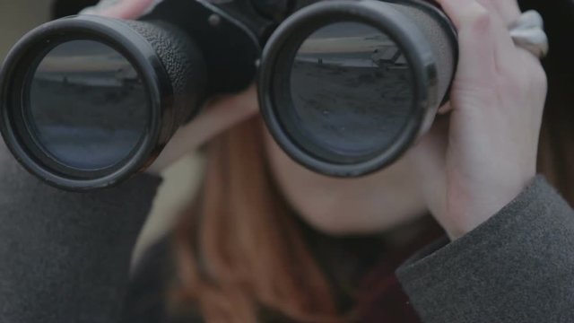 Ragazza sta osservando il mare con un binocolo