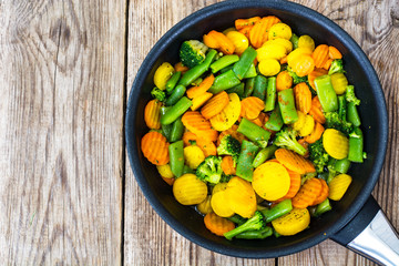 Stewed vegetables carrots, green beans and broccoli in a frying 