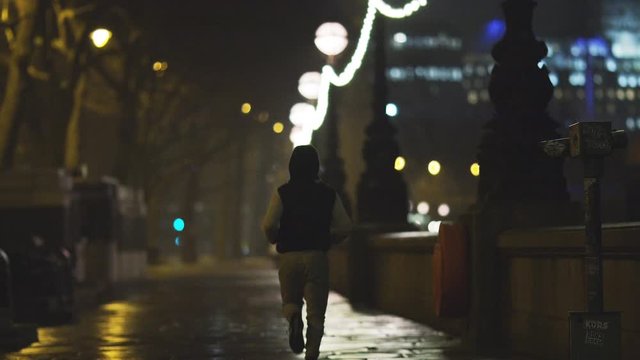 4K Young man running alone in the city at night, in slow motion