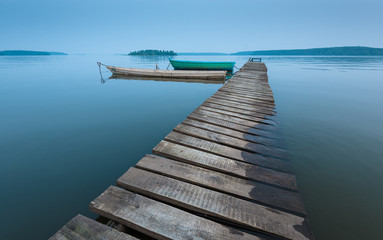 meditative landscape with old wooden pier and wooden boats, long exposure