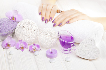 Fototapeta na wymiar beautiful pink manicure with orchid and towel on the white wooden table. spa
