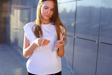 One young female woman unravels headphones for listening to musi