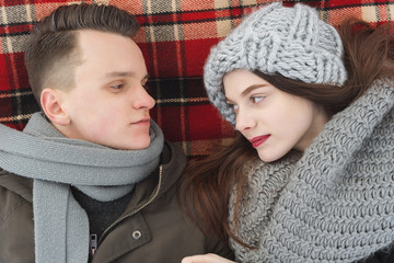 happy couple lying on a red plaid in winter