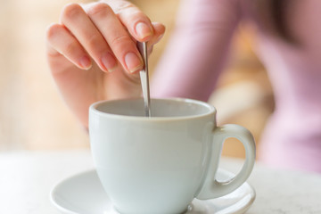 Beautiful young woman drinking coffee sitting by the window in t