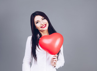 Beautiful girl holding a heart shape symbol in hands.   