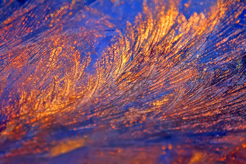 Icy frosty ornate pattern of thin ice on the window in the background of the dawn.