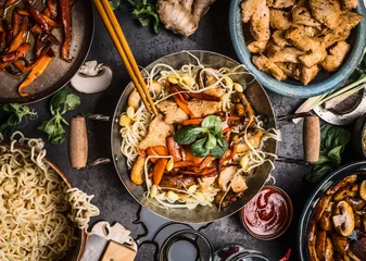 Crédence de cuisine en verre imprimé Manger Table de cuisine asiatique avec bols de nourriture, wok, sautés, baguettes et ingrédients sur fond, vue de dessus