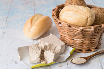 Yeast.   Yeast, fresh and dry granular, next to a wicker basket with fresh bread on a light wooden table.