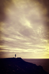 Woman standing on a cliff using her mobile phone