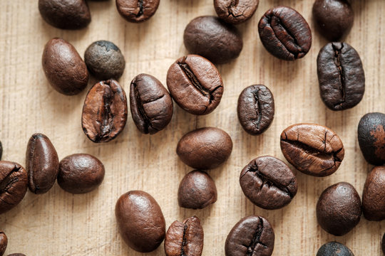 Detail view of coffee beans on wooden background. Macro shoot.