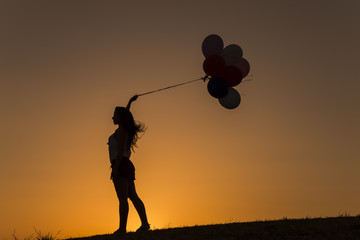 young woman with balloons at sunset