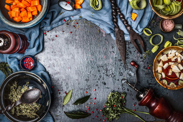 Dark rustic vegetarian food background with bowls of chopped vegetables and seasoning  ingredients and kitchen tools, top view, frame. Vegan or vegetarian nutrition, diet and healthy food concept