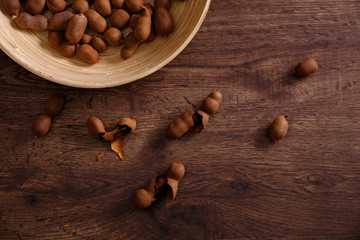 Sweet tamarind on grunge rustic wood background. Natural organic diet food with a lot of vitamins. Plate dish or bowl on wooden board.