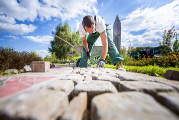 Handwerker verlegt Pflastersteine in einer Gartenanlage 