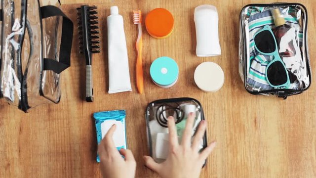 hands packing cosmetic bag with stuff for travel