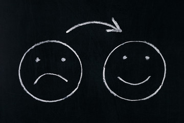 Handing drawing faces emotions on blackboard.Changing mood from bad to good.