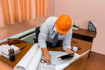 Engineer in helmet working with drawings