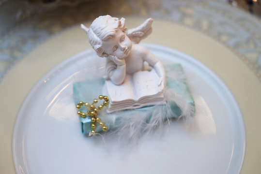 Close up photo of Festive table decoration with white plaster angel on plate.
