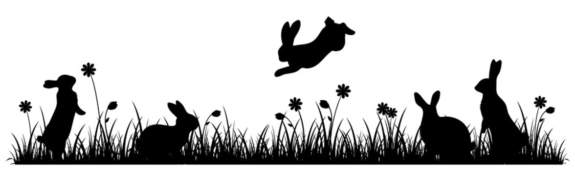 Silhouettes of Easter bunnies on a flower meadow