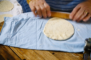 Women hands chef rolling pita dough with rolling pin..
