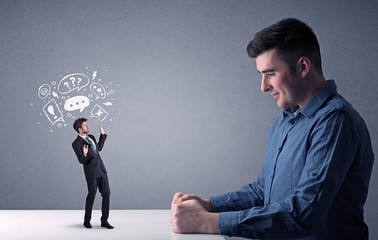 Young businessman fighting with miniature businessman