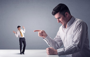 Young businessman fighting with miniature businessman