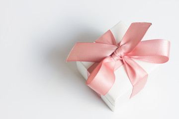 Gift box with pink ribbon on white table