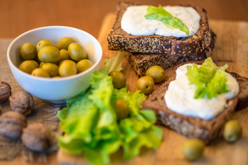 Vegetarian breakfast. Homemade bread with cheese sauce, olives in bowl, walnuts 