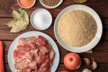 Cooking ingredients. Sliced raw meat, rice, spices, garlic, carrot, onion, bay