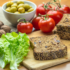 Fresh organic vegetables: tomatoes, olives in bowl, walnuts, lettuce and homemad