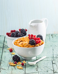 Oat and cornflakes with fresh berries on white bowl on old board with free text space. Selective focus.