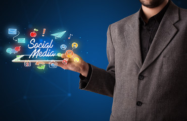 Businessman holding tablet with social media graphics