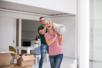 couple carrying a carpet moving in to new home