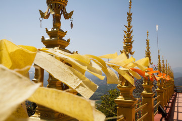 Flying and waving yellow and orange buddhist flags in thai temple with sky background 