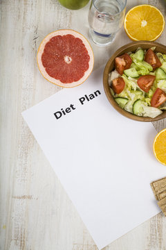 Food and sheet of paper with a diet plan on a  wooden table.