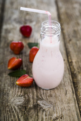 Smoothies and ripe strawberry on a wooden table.