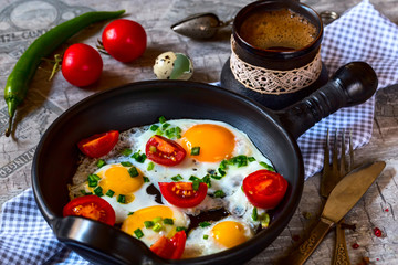 Scrambled eggs with tomatoes in a pan on a gray table