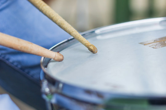 A snare drum and a pair of drumsticks.