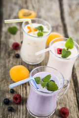 Smoothies or yogurt with fresh berries on a wooden table.