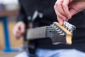 Close up of guitarist hand tuning electric guitar