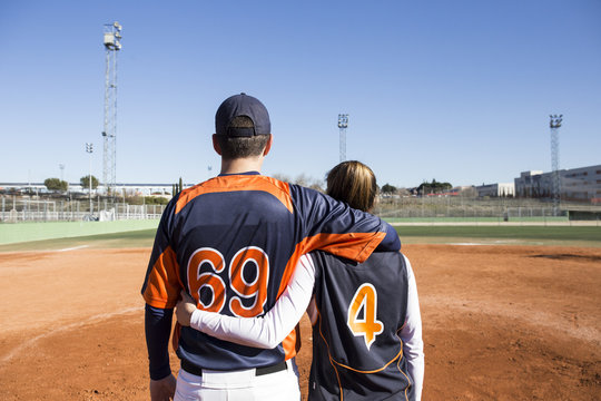 Rear view of baseball players embracing on a baseball field