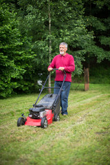 Senior man mowing the lawn in his garden
