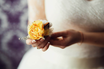 gentle hand of the bride holding boutonniere for the groom