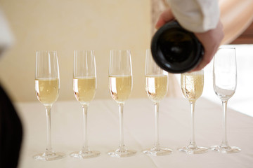waiter pours champagne in glasses for guests