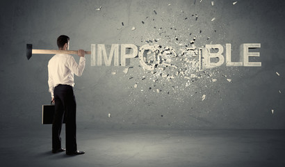 Fototapeta premium Business man hitting impossible sign with hammer